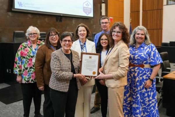 Group photo of researchers presenting a plaque